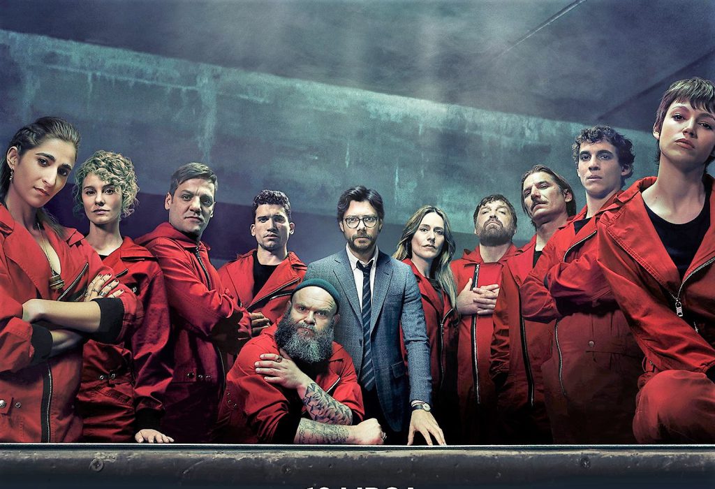 Dom z papieru 3, na zdjęciu główni bohaterowie serialu, stoją w grupie lub podpierają się o stół.