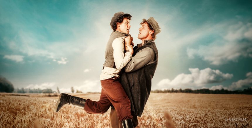 two men holding each other in a wheat field